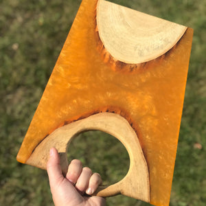 ash cookie cut in two with unique handle running through the wood so you can grib it easily and display meat and cheese on the orange epoxy charcuterie board